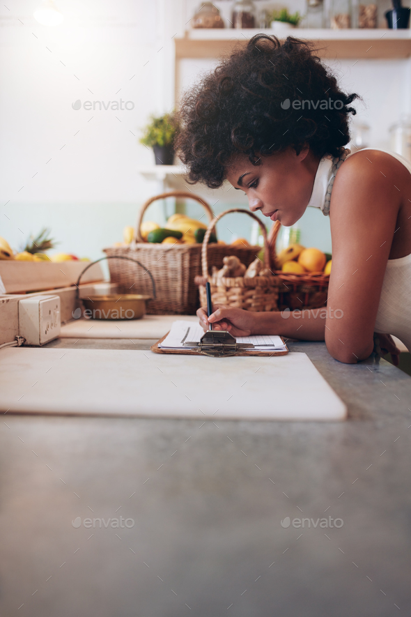 Female juice bar owner calculating expenses Stock Photo by jacoblund